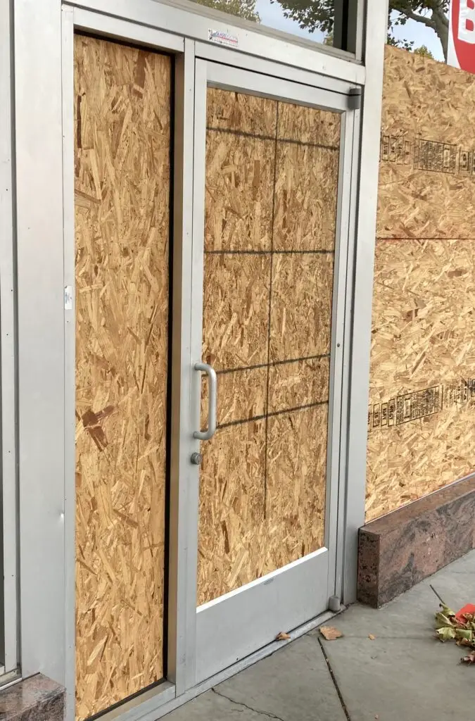 Emergency window board-up service: a technician securely installing plywood over a broken window, providing immediate protection and safety for the property.