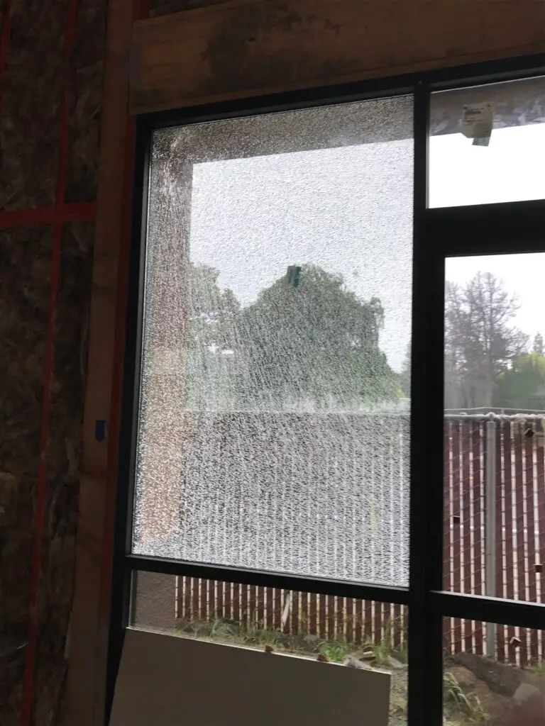 Broken insulated glass unit (IGU) in a storefront: shattered glass panels and a damaged frame, highlighting the need for urgent replacement to ensure security and aesthetic